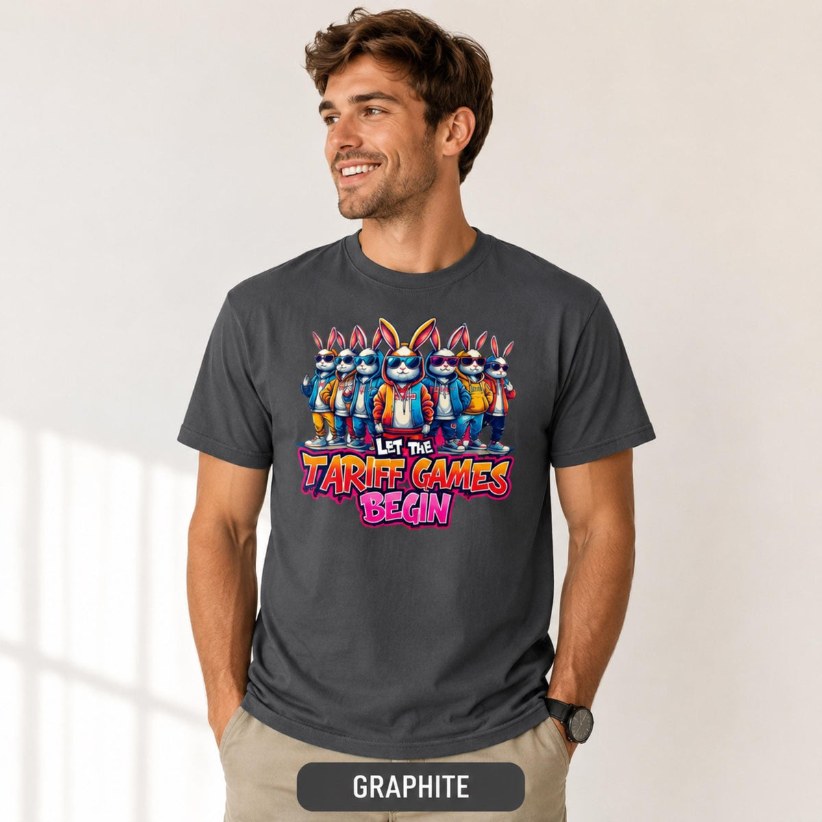 Male model wearing a graphite T-shirt featuring stylish cartoon rabbits and bold “Let the Tariff Games Begin” text.