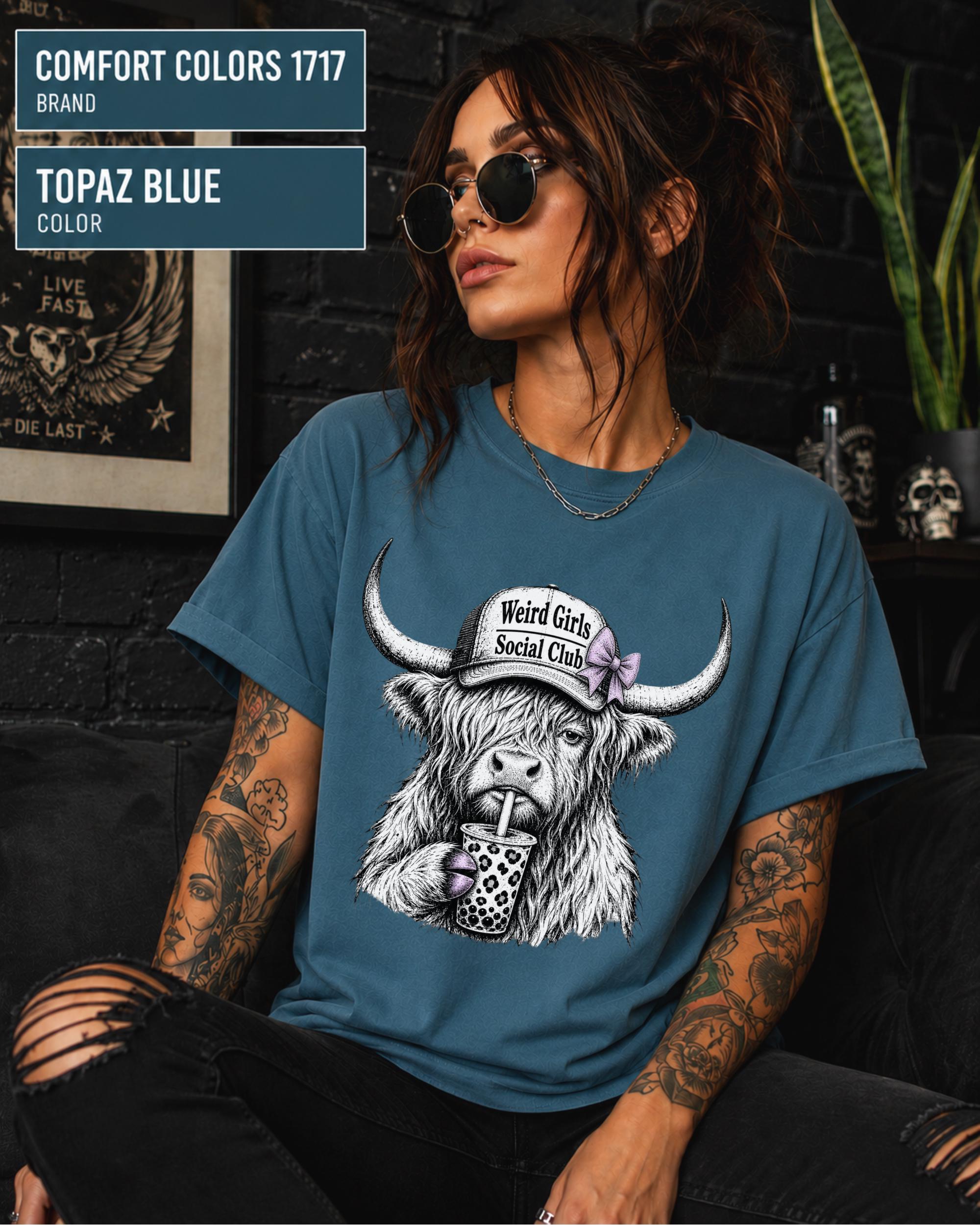 Comfort Colors Topaz Blue tee featuring detailed black-and-white cow artwork with soft purple accents.