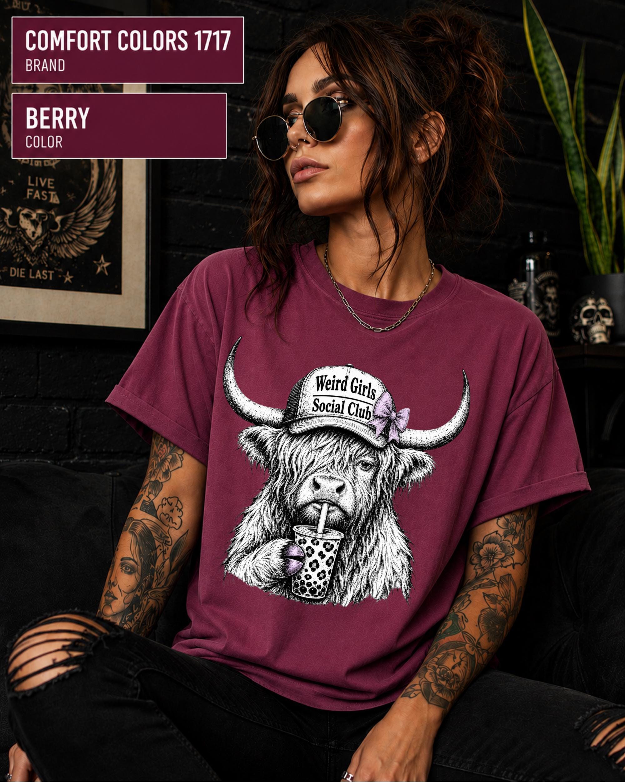 Relaxed unisex cow tee photographed in a dark alternative room with skull decorations and black walls.
