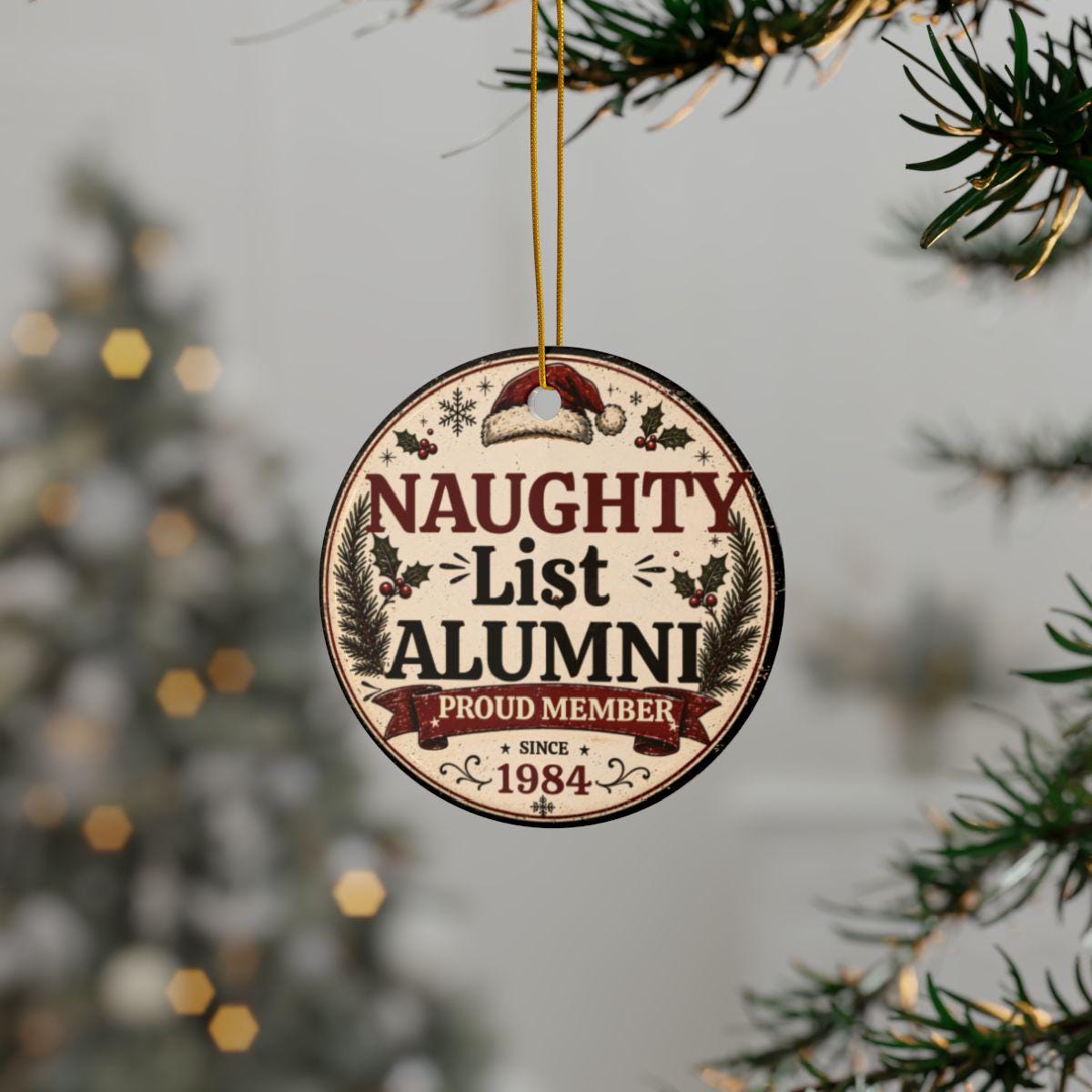 Naughty List Alumni ceramic Christmas ornament hanging on a decorated holiday tree with festive lights.