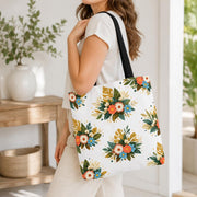 Floral tote bag featuring coral, cream, and blue flowers with green and golden leaves.