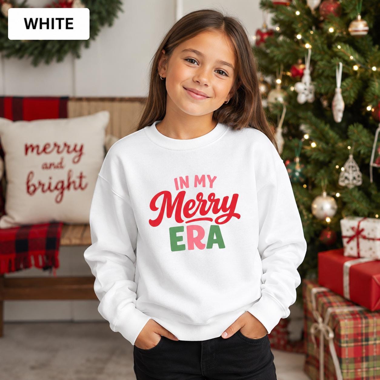 Young girl wearing a white In My Merry Era youth Christmas sweatshirt in a festive living room.