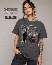 Woman wearing a Pepper Comfort Colors 1717 shirt featuring a stylish opossum inside a vintage laundromat.