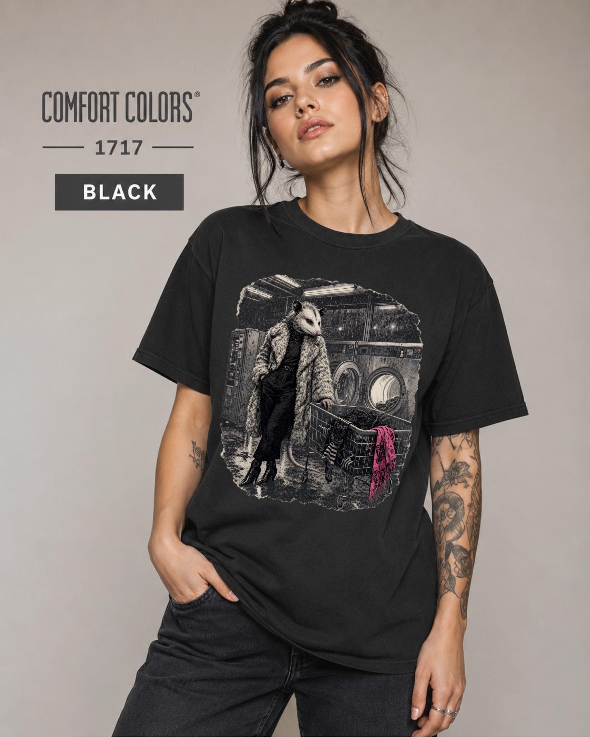 Gothic animal graphic tee showing an opossum in a dramatic coat pushing a laundry cart.