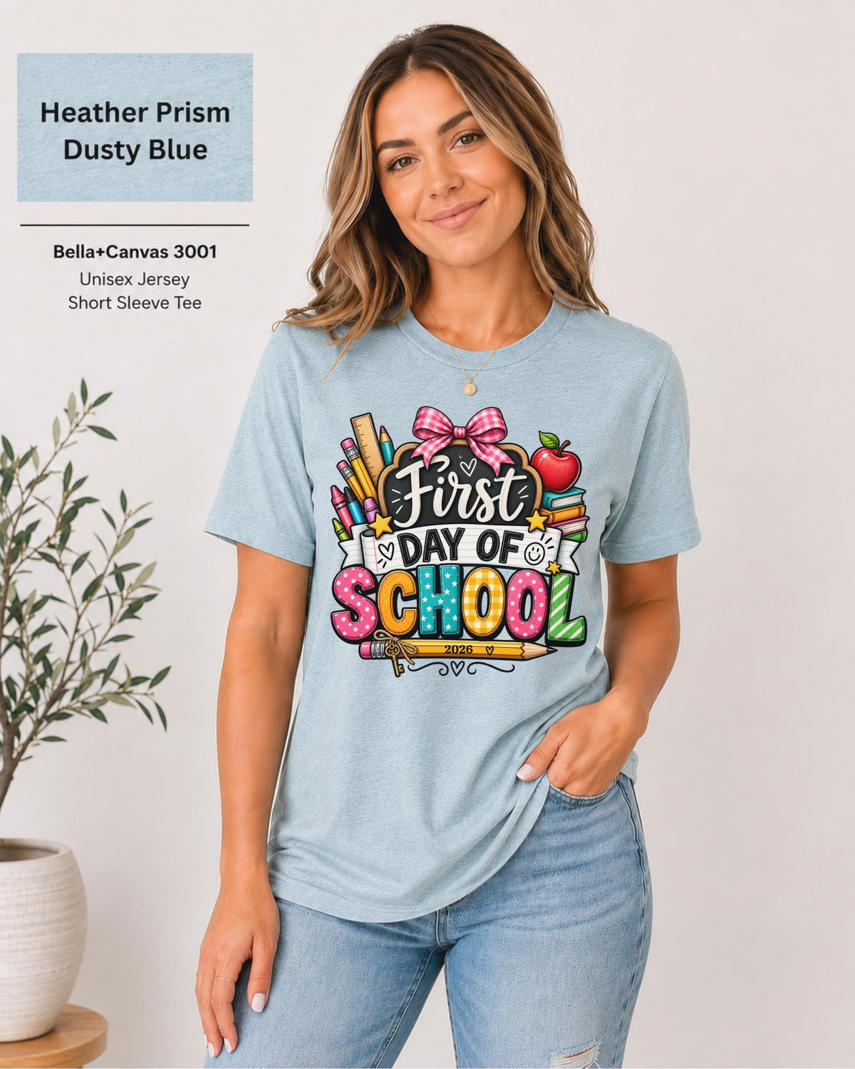 Woman wearing an Heather Prism Dusty Blue Bella+Canvas 3001 personalized First Day of School shirt with customizable teacher name and year, colorful pencils, crayons, books, apple, and pink bow design.