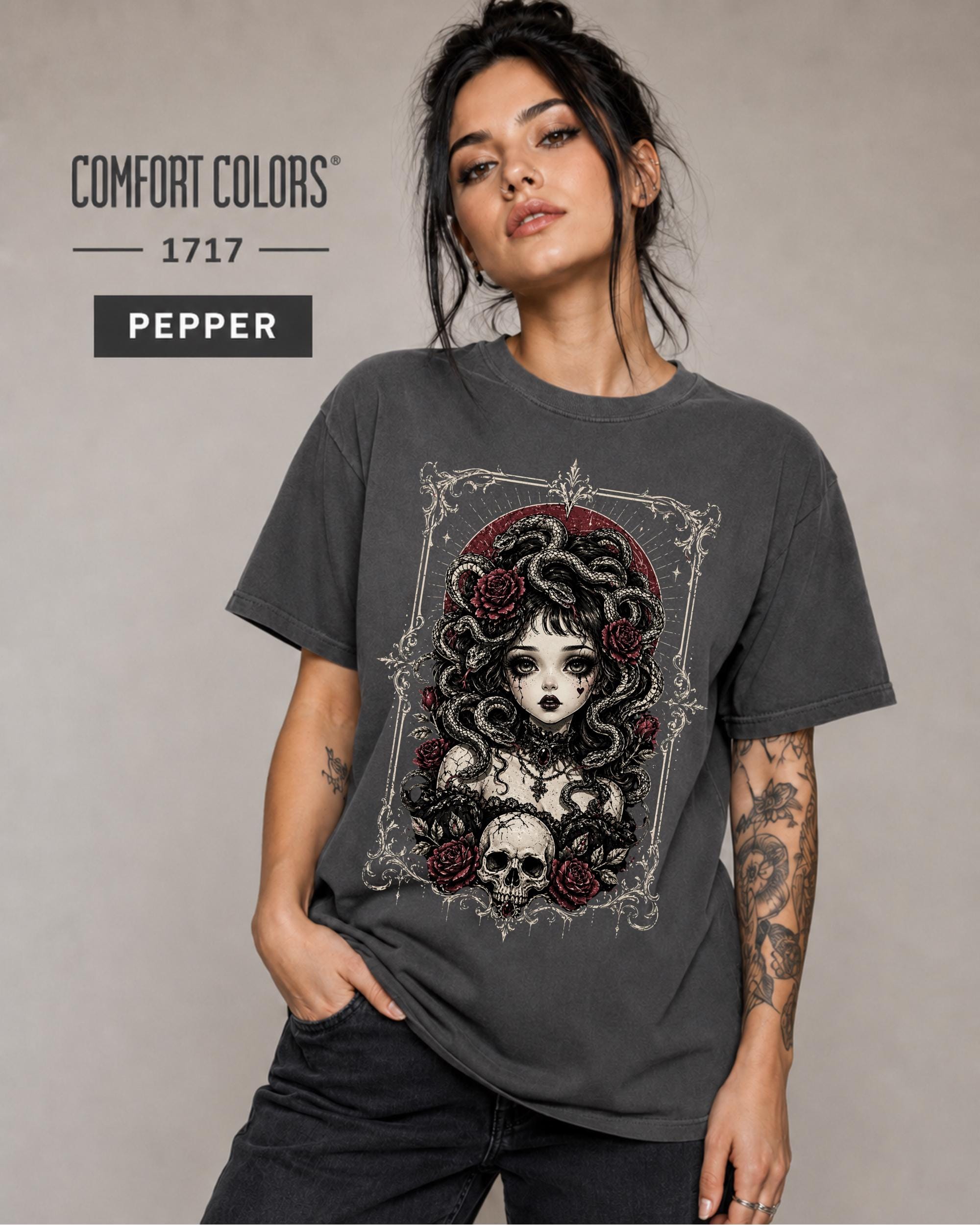 Woman wearing a Pepper Comfort Colors 1717 T-shirt featuring a gothic Medusa-inspired woman with snakes, dark roses, ornate framing, and a skull design.