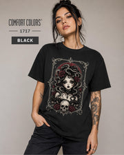 Woman wearing a Black Comfort Colors 1717 T-shirt featuring a gothic Medusa-inspired woman with snakes, dark roses, ornate framing, and a skull design.