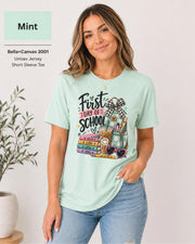 Woman wearing a Mint Bella+Canvas 3001 First Day of School teacher shirt with colorful classroom artwork.