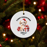 Custom First Christmas ceramic ornament with Santa artwork and the name Oliver, hanging from a festive evergreen tree decorated with red ornaments and warm Christmas lights.