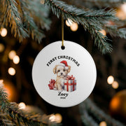 Personalized First Christmas ornament hanging on a Christmas tree with warm golden lights, featuring a festive Santa illustration, custom name Oliver, and a round white keepsake design.