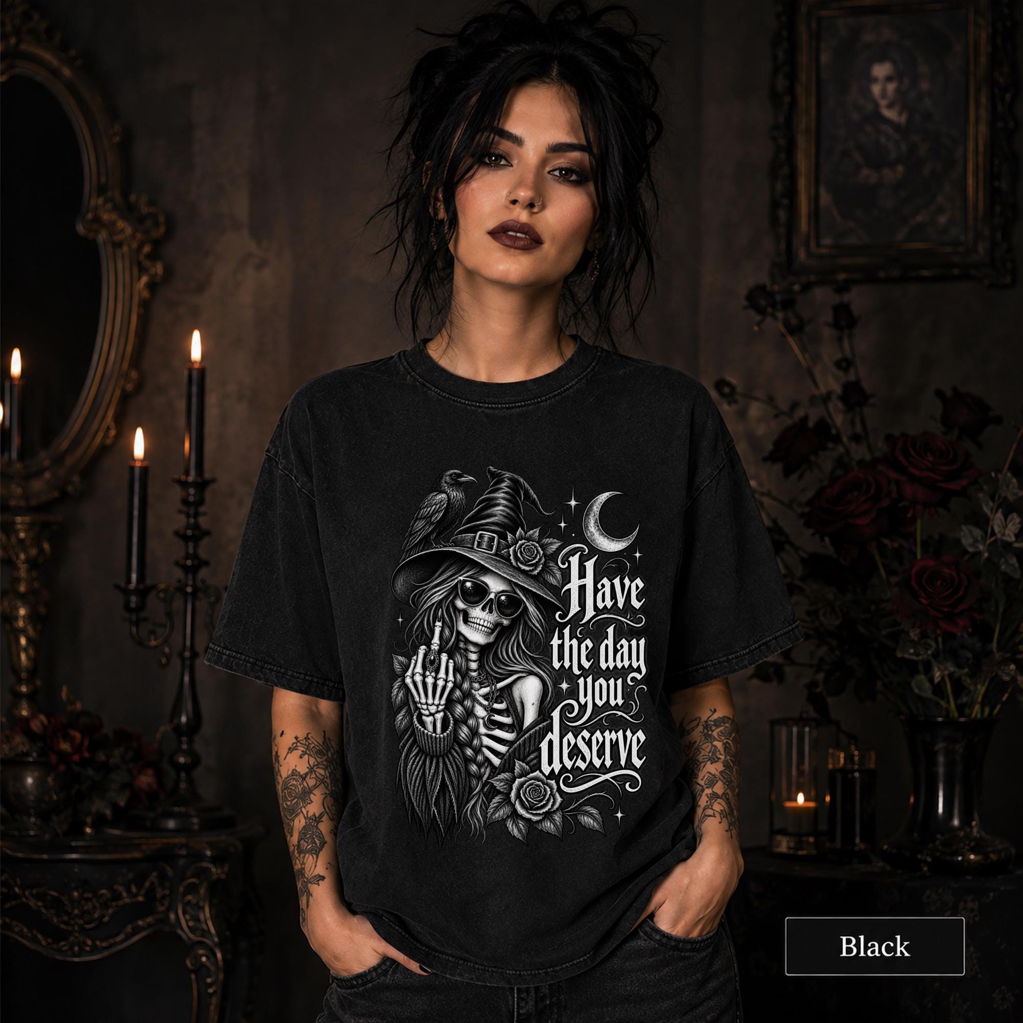 Woman wearing a black gothic shirt featuring a skeleton witch, raven, crescent moon, roses, and Have the Day You Deserve text.