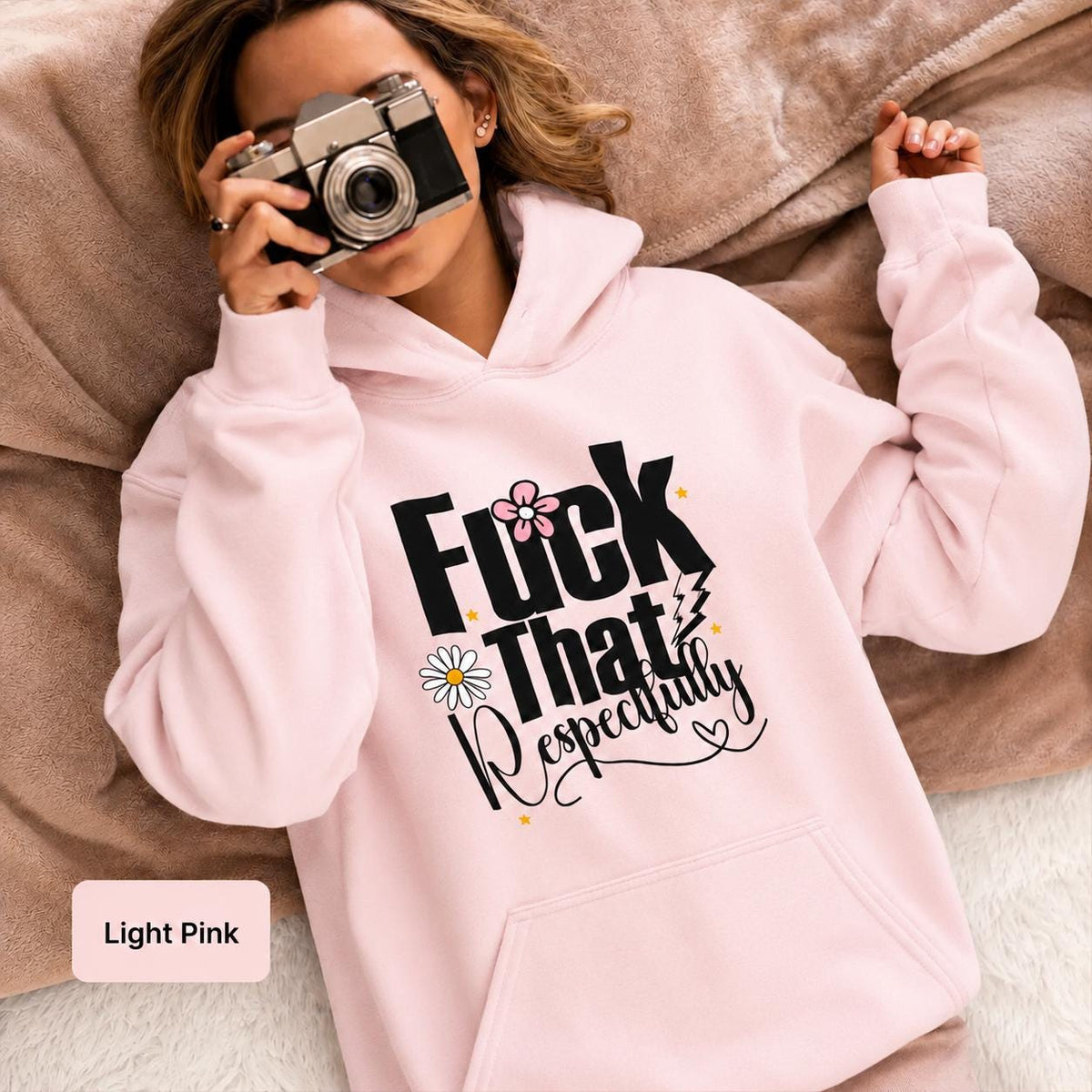 Light pink Gildan 18500 hoodie modeled by a woman with a vintage camera, featuring playful “Fuck That Respectfully” typography and floral accents.