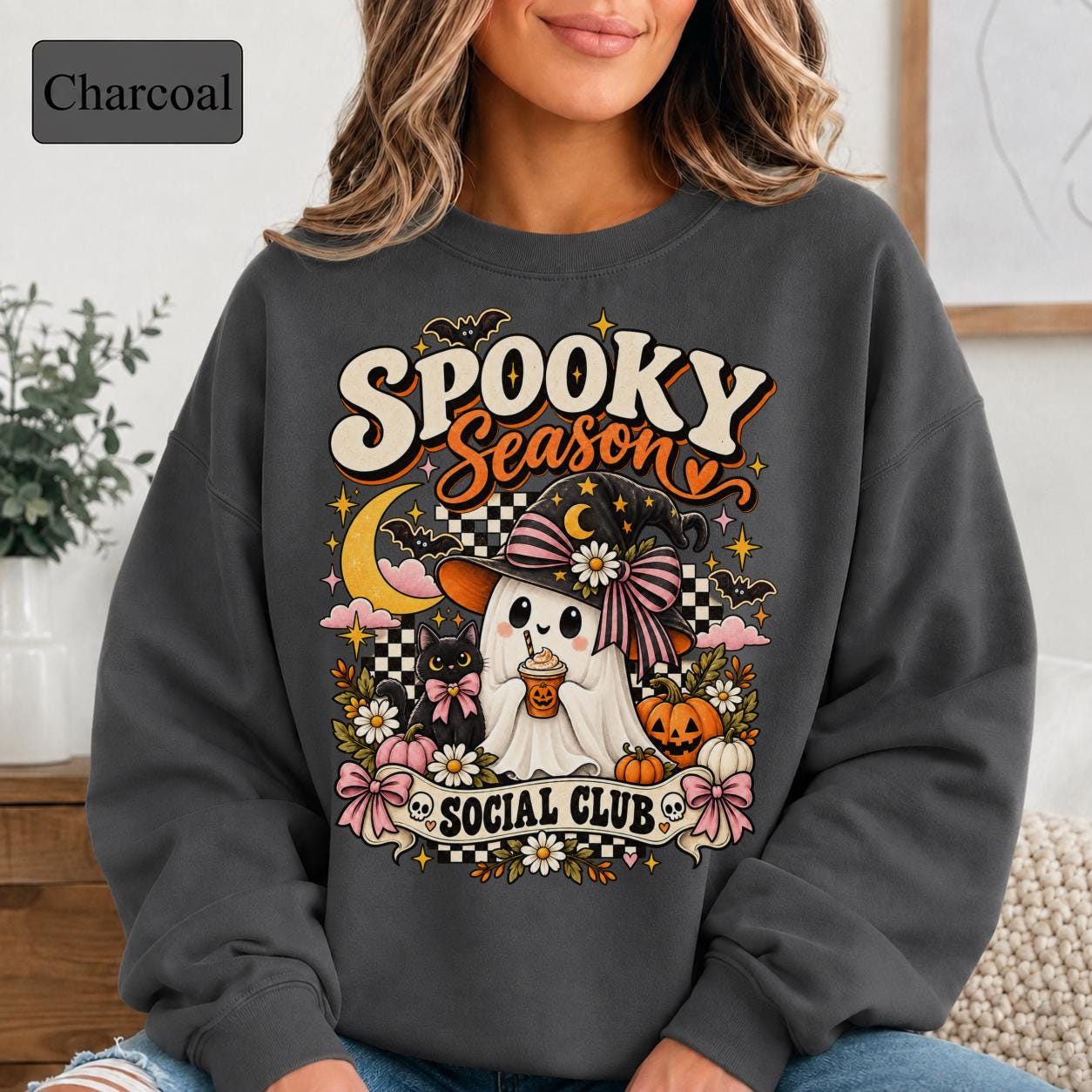 Cute Halloween sweatshirt featuring a ghost in a witch hat, black cat, pumpkins, daisies, bats, and checkerboard accents.