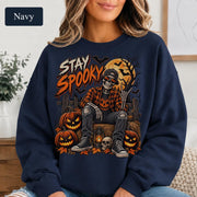 Navy Halloween sweatshirt featuring a Stay Spooky skeleton graphic with jack-o’-lanterns, full moon, bats, autumn leaves, and orange fall details.