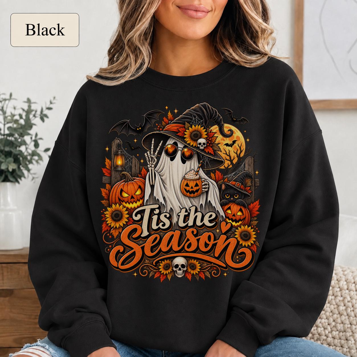 Woman wearing a black Tis the Season Halloween sweatshirt with ghost, pumpkins, black cat, sunflowers, and bats.