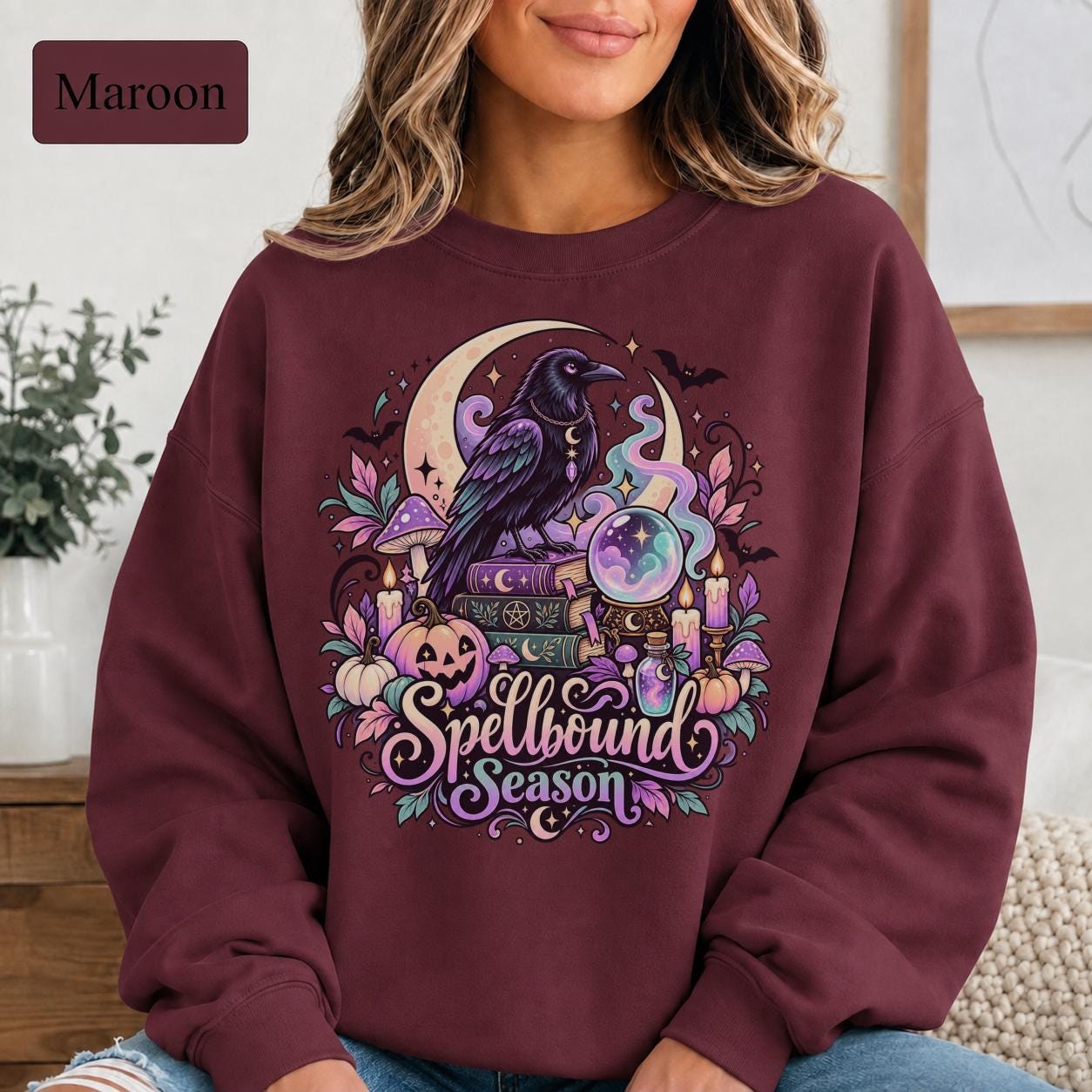 Witchy Halloween crewneck with raven artwork surrounded by pastel pink, purple, teal, and cream details.