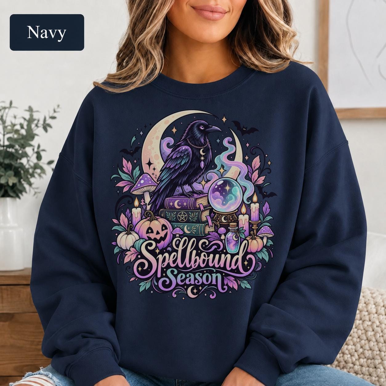 Mystical raven sweatshirt featuring crystal ball, potion bottle, mushrooms, pumpkins, bats, and celestial stars.