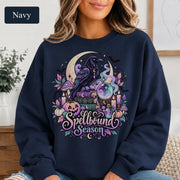 Mystical raven sweatshirt featuring crystal ball, potion bottle, mushrooms, pumpkins, bats, and celestial stars.