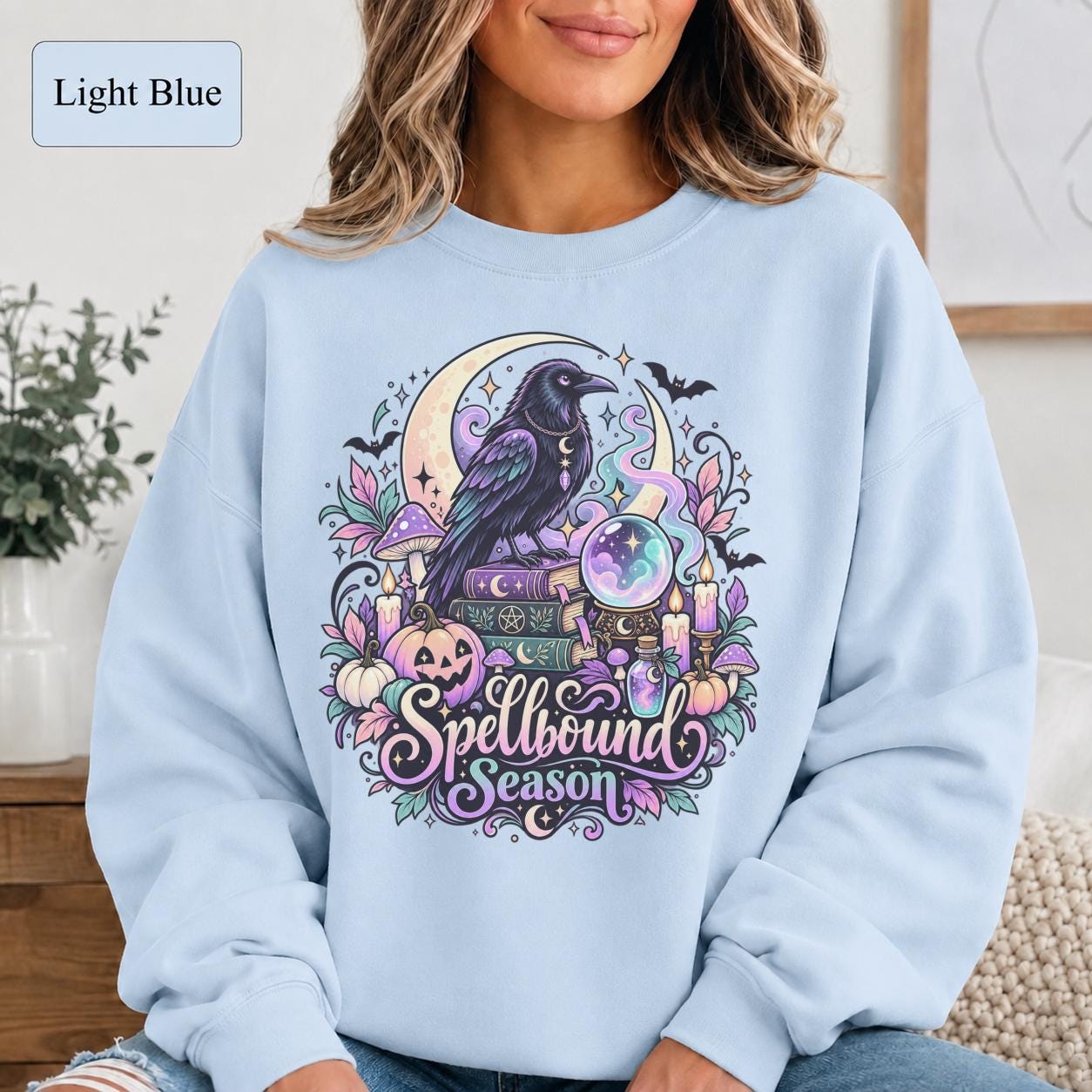 Raven lover sweatshirt featuring magical books, moon symbols, potion bottle, candles, and Halloween accents.