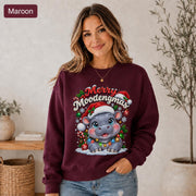 Maroon Christmas sweatshirt featuring a cute hippo in a Santa hat with Merry Moodengmas text, candy canes, ornaments, holly, and snowflakes.