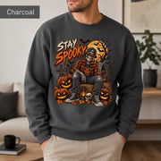 Charcoal Halloween sweatshirt featuring a Stay Spooky skeleton graphic with jack-o’-lanterns, full moon, bats, autumn leaves, and orange fall details.