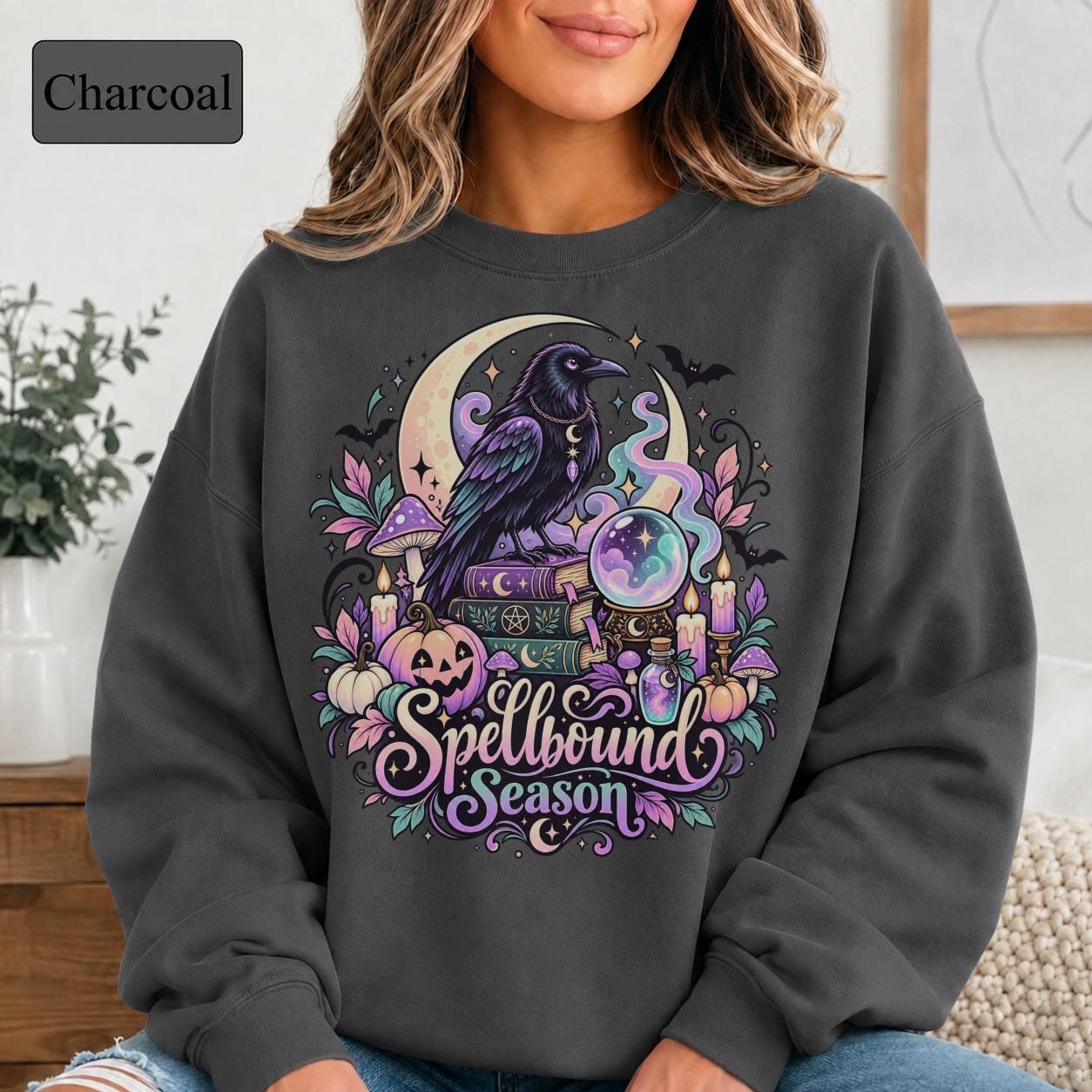 Celestial witchy crewneck with black raven, glowing orb, pumpkins, mushrooms, and decorative leaves.