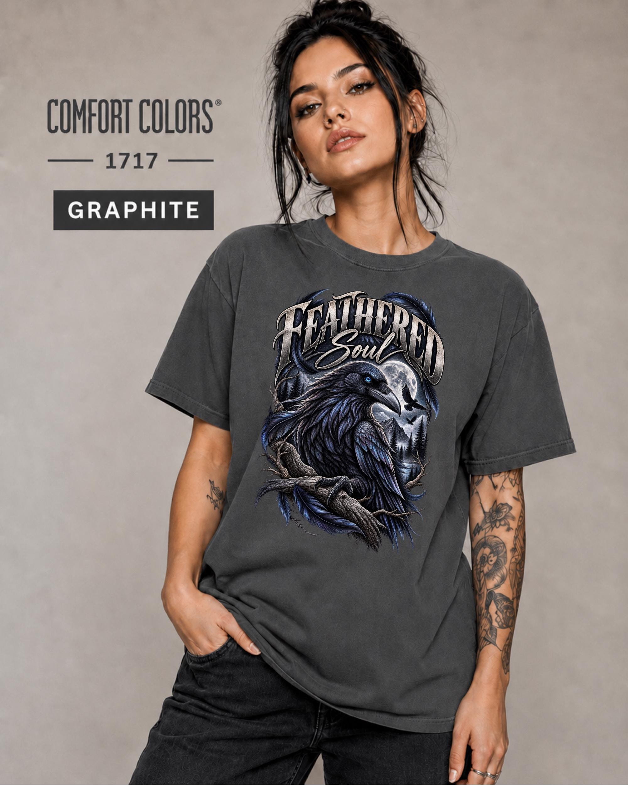 Feathered Soul raven graphic Comfort Colors 1717 T-shirt in graphite featuring a detailed black raven with a blue eye, moonlit forest, branches, and gothic artwork.