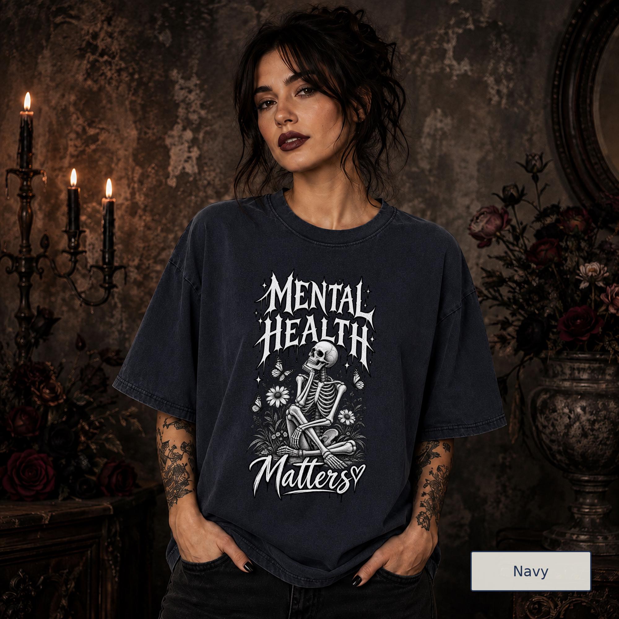 Mental Health Matters navy T-shirt featuring a seated skeleton, flowers, butterflies, and bold gothic lettering in a monochrome design.