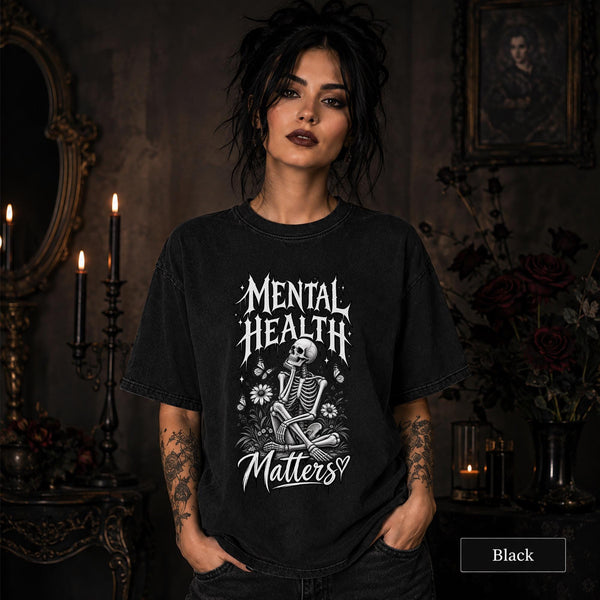 Mental Health Matters black T-shirt featuring a seated skeleton, flowers, butterflies, and bold gothic lettering in a monochrome design.