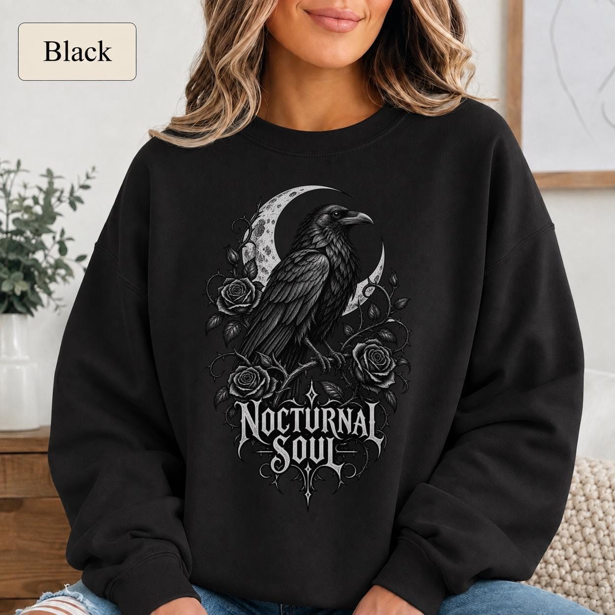 Woman wearing a blackl crewneck sweatshirt featuring a detailed black raven surrounded by a crescent moon, thorny roses, and Nocturnal Soul lettering.