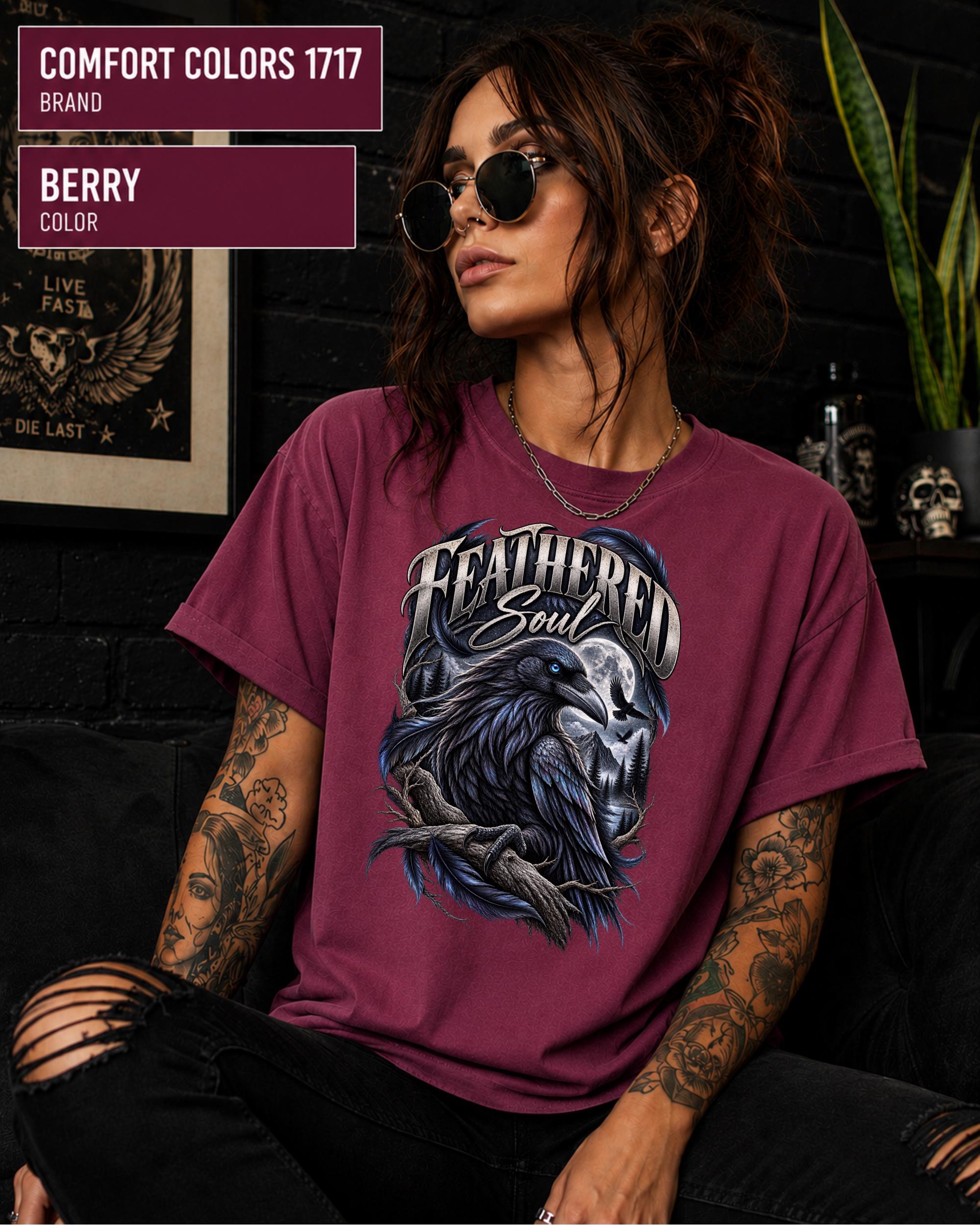 Feathered Soul raven graphic Comfort Colors 1717 T-shirt in berry featuring a detailed black raven with a blue eye, moonlit forest, branches, and gothic artwork.