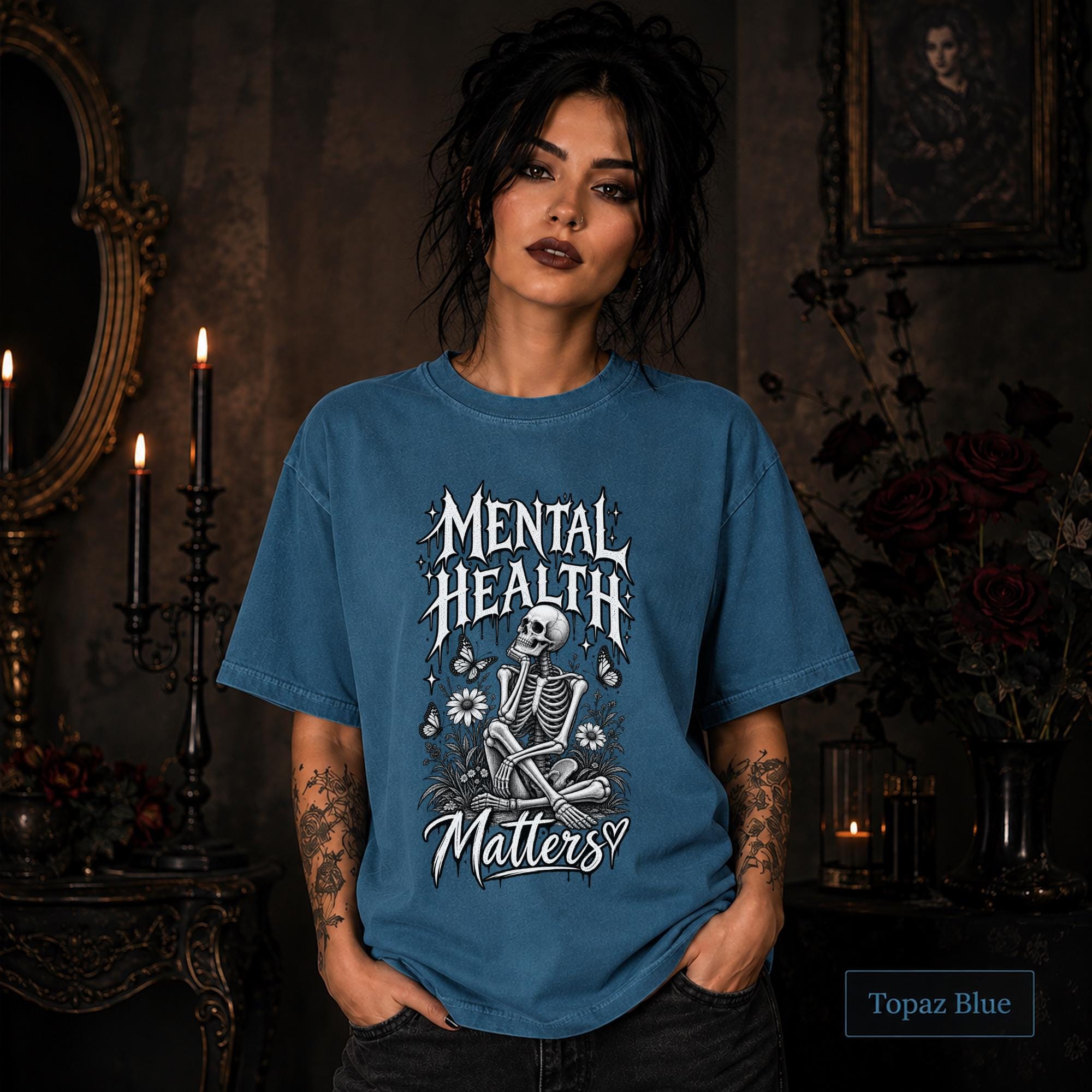 Mental Health Matters topaz blue T-shirt featuring a seated skeleton, flowers, butterflies, and bold gothic lettering in a monochrome design.