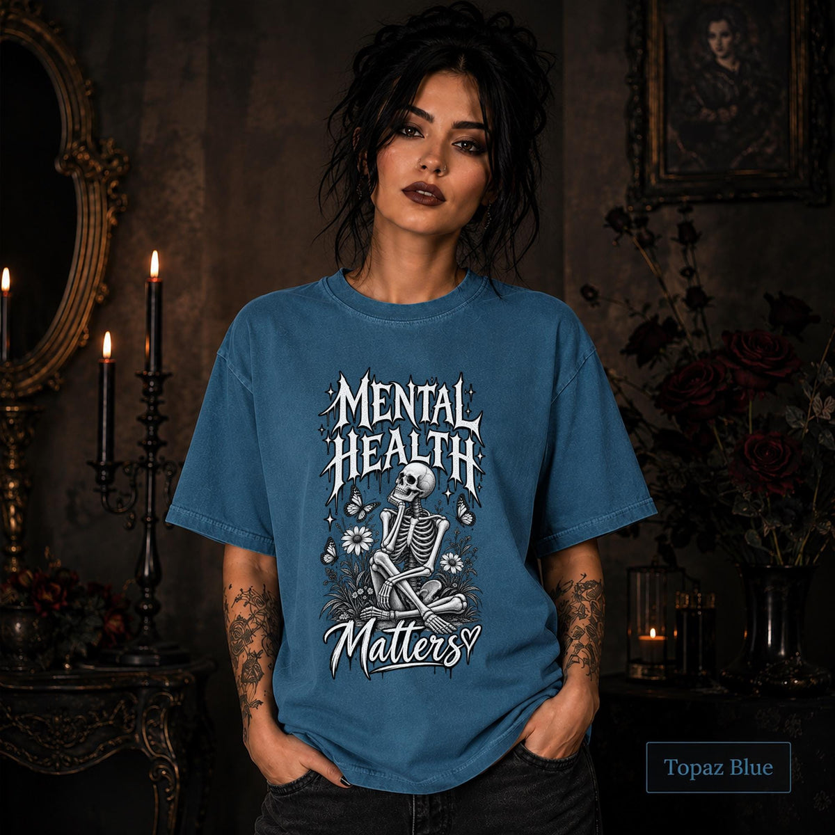 Mental Health Matters topaz blue T-shirt featuring a seated skeleton, flowers, butterflies, and bold gothic lettering in a monochrome design.