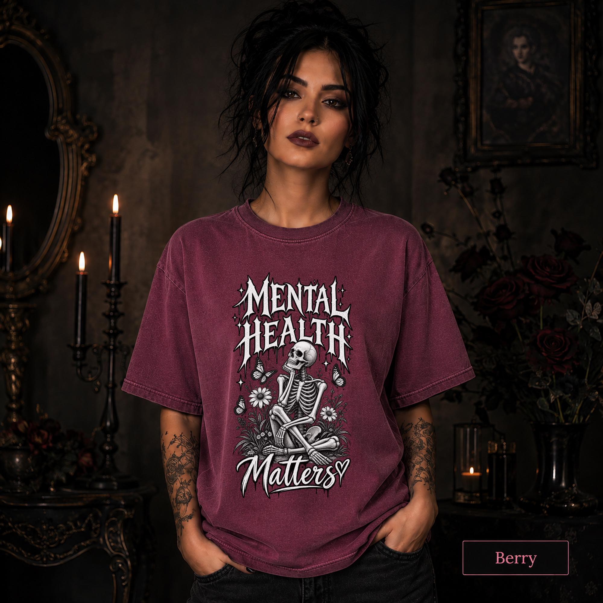 Mental Health Matters berry T-shirt featuring a seated skeleton, flowers, butterflies, and bold gothic lettering in a monochrome design.
