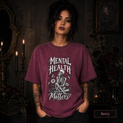 Mental Health Matters berry T-shirt featuring a seated skeleton, flowers, butterflies, and bold gothic lettering in a monochrome design.