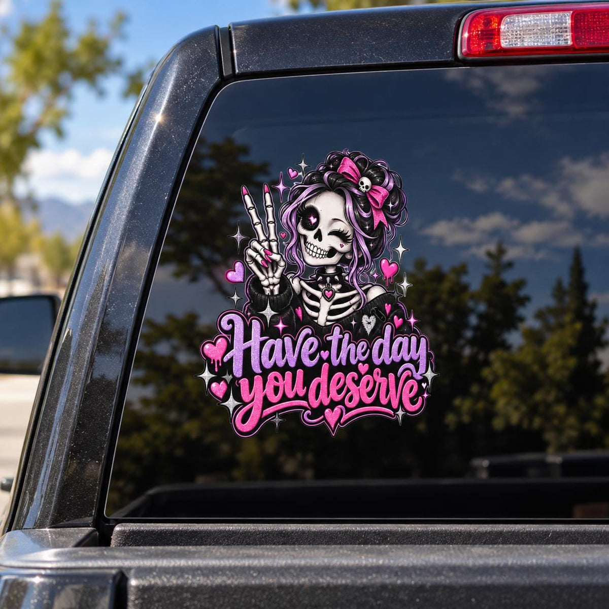 Have the Day You Deserve skeleton decal displayed on a truck rear window with cute goth pink, purple, black, and white artwork.