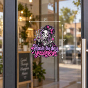 Have the Day You Deserve gothic skeleton girl UV DTF decal shown on a glass door with pink and purple hearts, sparkles, bow, and peace sign.