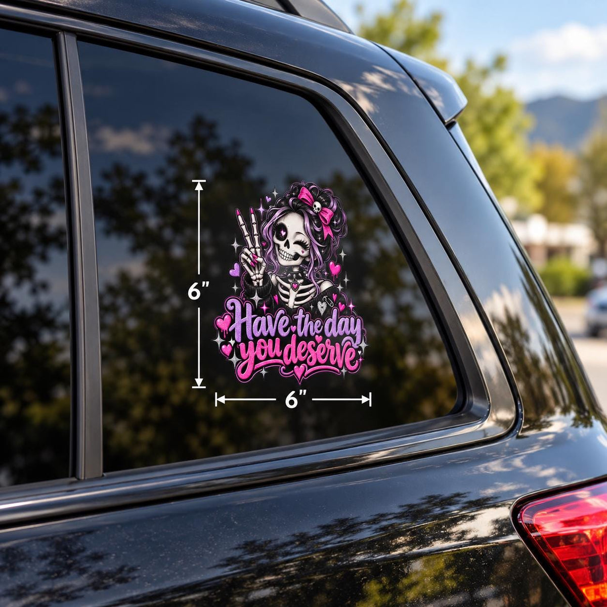 Have the Day You Deserve car window decal featuring a smiling skeleton girl with pink bow, peace sign, hearts, and pastel goth details.