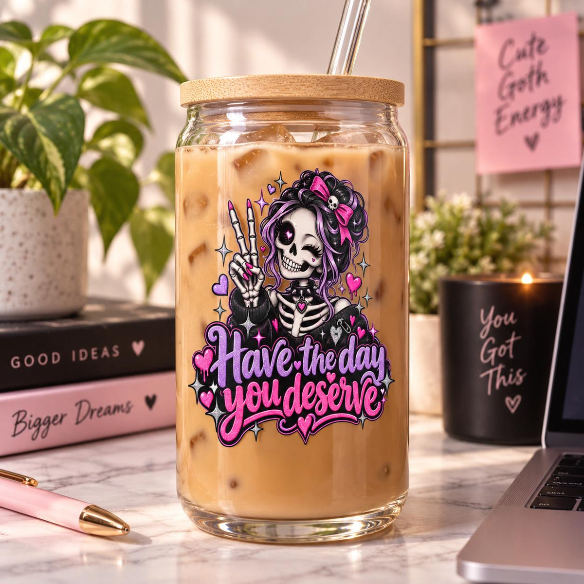 Have the Day You Deserve UV DTF sticker shown on a clear iced coffee tumbler with cute skeleton girl, hearts, sparkles, and bold pink text.