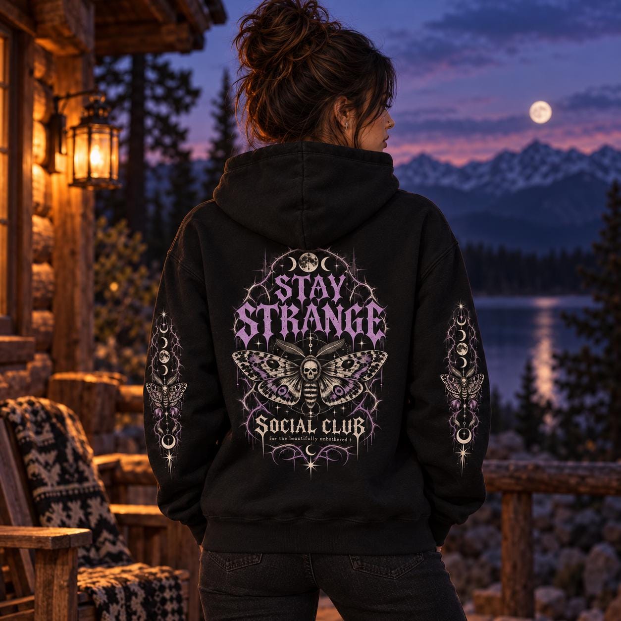 Black Stay Strange Social Club heavyweight hoodie featuring purple gothic lettering, death’s-head moth artwork, moon phases, thorn details, and matching celestial sleeve designs.