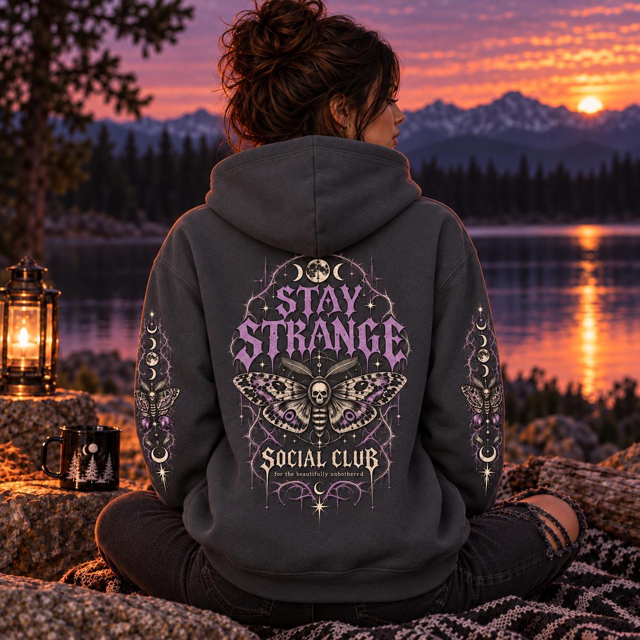 Charcoal Stay Strange Social Club heavyweight hoodie featuring purple gothic lettering, death’s-head moth artwork, moon phases, thorn details, and matching celestial sleeve designs.