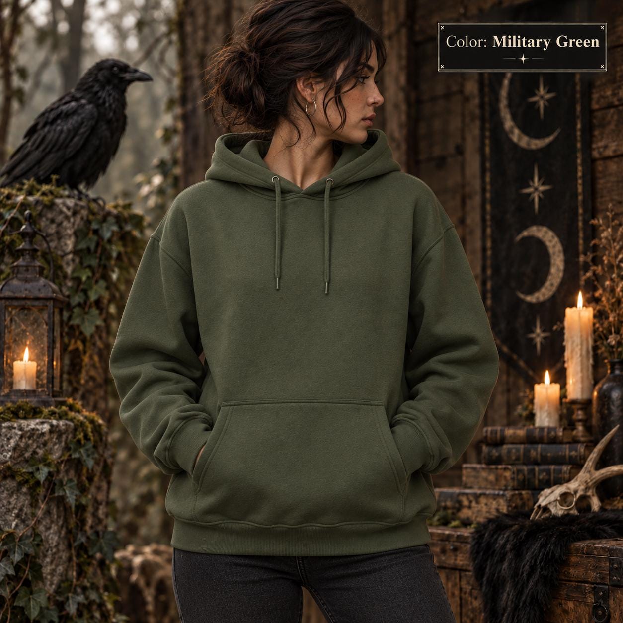 Military Green unisex hoodie shown from the front, featuring a large purple raven perched on the back against a glowing violet moon, surrounded by mountains, pine trees, mist, and celestial details.