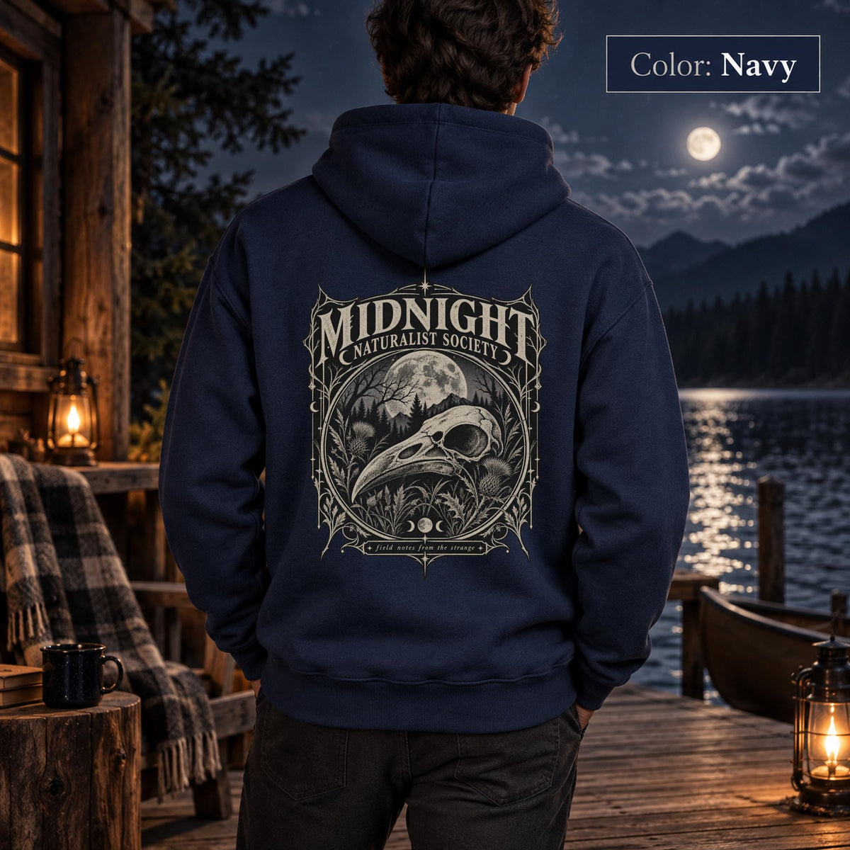 Navy unisex hoodie shown from the back with a large Midnight Naturalist Society graphic featuring a bird skull, moon, mountains, forest plants, and vintage gothic botanical details.