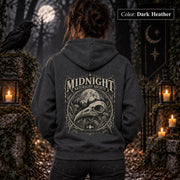 Dark Heather unisex hoodie shown from the back with a large Midnight Naturalist Society graphic featuring a bird skull, moon, mountains, forest plants, and vintage gothic botanical details.
