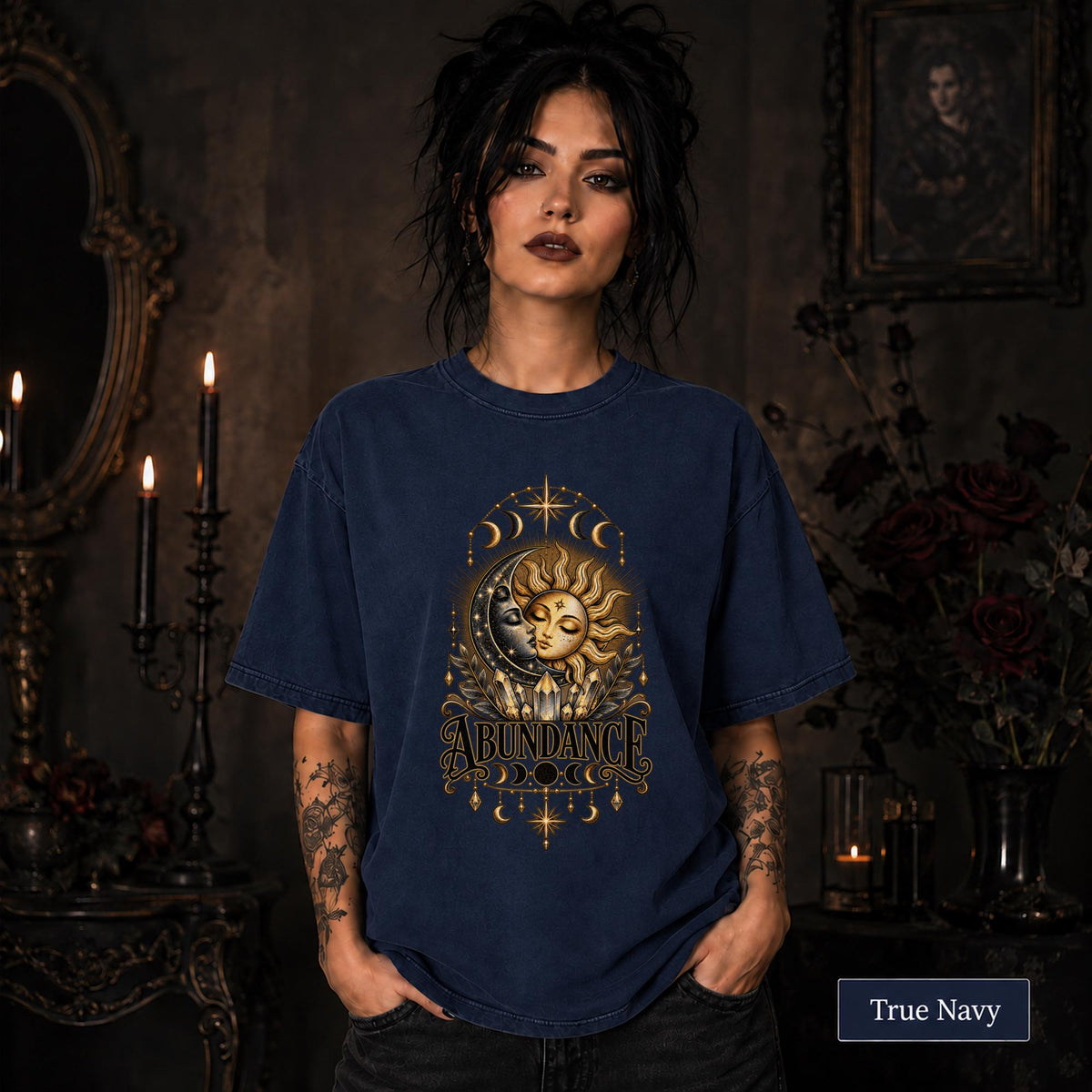 Female model wearing a true navy Comfort Colors 1717 shirt with a gold celestial Abundance design featuring sun and moon faces, crystals, stars, and moon phases.