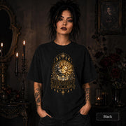 Female model wearing a black Comfort Colors 1717 shirt with a gold celestial Abundance design featuring sun and moon faces, crystals, stars, and moon phases.
