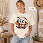 Just a Girl Who Loves Halloween T-shirt in ivory featuring a floral tombstone design with bats, orange and pink flowers, hearts, sparkles, and a pink bow.