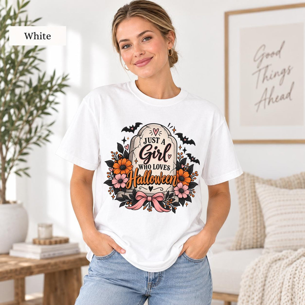 Just a Girl Who Loves Halloween T-shirt in white featuring a floral tombstone design with bats, orange and pink flowers, hearts, sparkles, and a pink bow.