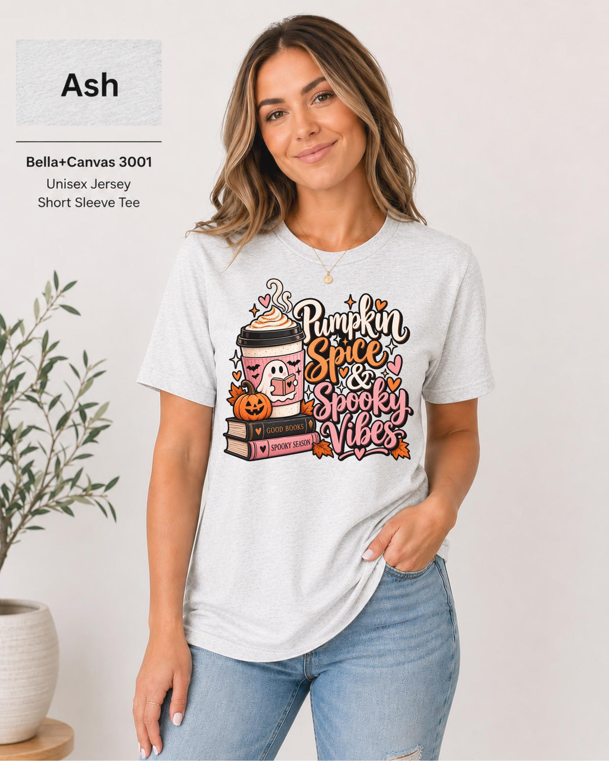 Bella+Canvas 3001 Ash unisex T-shirt featuring a “Pumpkin Spice & Spooky Vibes” design with a ghost reading, fall coffee, stacked books, jack-o’-lantern, hearts, and autumn leaves.