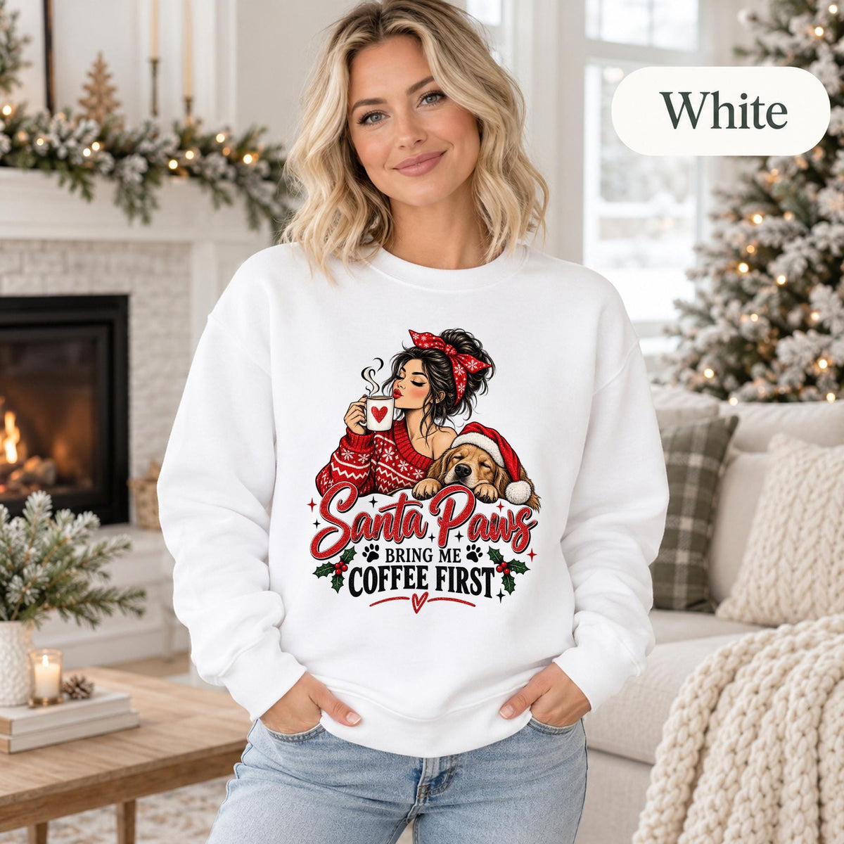 White crewneck sweatshirt featuring a festive “Santa Paws Bring Me Coffee First” design with a woman holding a mug beside a dog in a Santa hat, shown on a female model in a cozy Christmas setting.